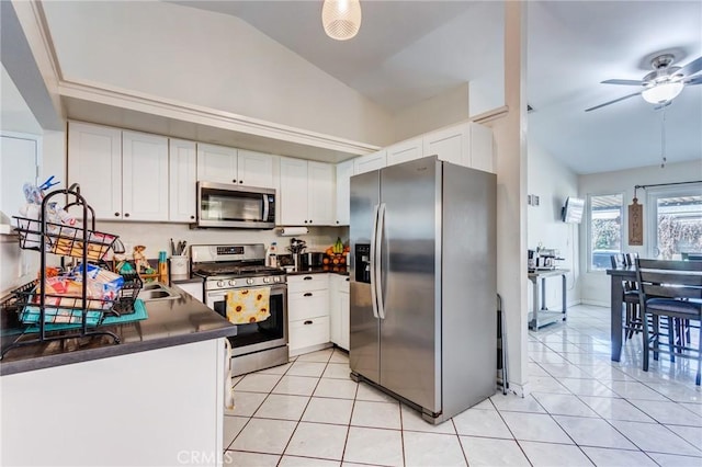 kitchen featuring a ceiling fan, dark countertops, appliances with stainless steel finishes, vaulted ceiling, and white cabinetry