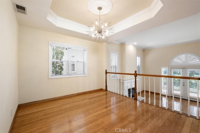 unfurnished room featuring crown molding, a chandelier, hardwood / wood-style floors, a wealth of natural light, and visible vents