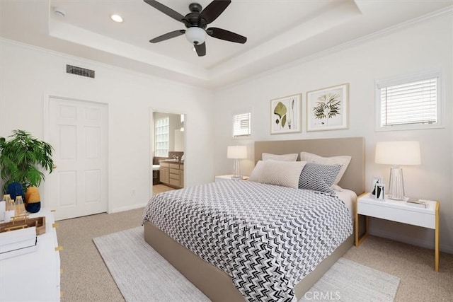 bedroom with multiple windows, light carpet, a tray ceiling, and visible vents