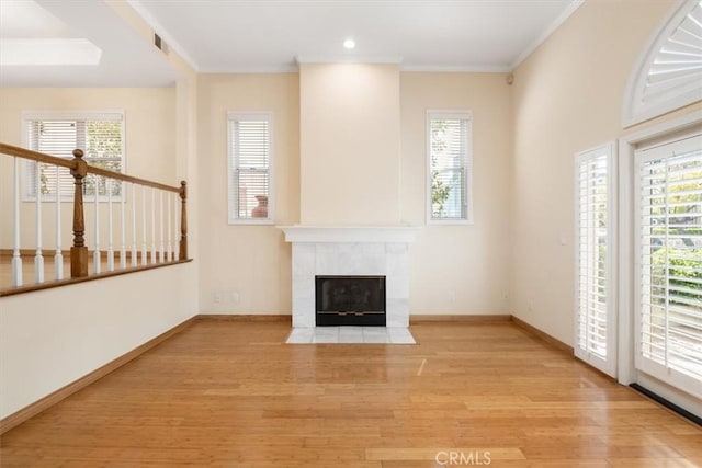 unfurnished living room featuring a fireplace, baseboards, wood finished floors, visible vents, and ornamental molding