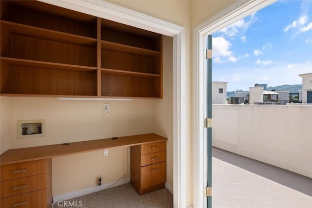 unfurnished office with built in study area, baseboards, and light carpet