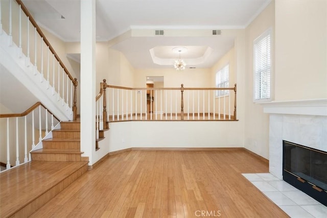 unfurnished living room with stairway, visible vents, hardwood / wood-style flooring, and a fireplace