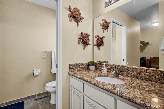 bathroom with visible vents, vanity, toilet, baseboards, and tile patterned floors