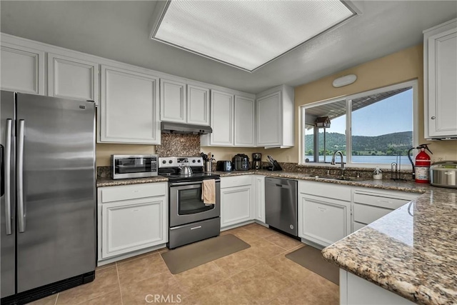 kitchen with a sink, white cabinetry, appliances with stainless steel finishes, and under cabinet range hood