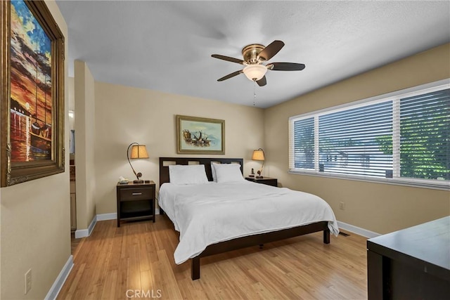 bedroom featuring baseboards, multiple windows, and light wood finished floors