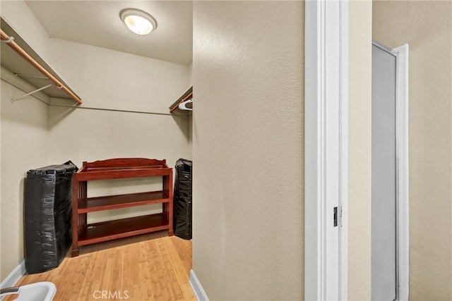 walk in closet with wood finished floors