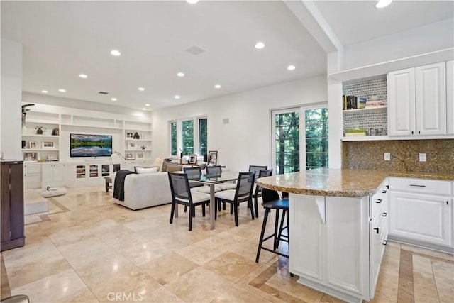 kitchen featuring light stone counters, white cabinets, open shelves, and a peninsula