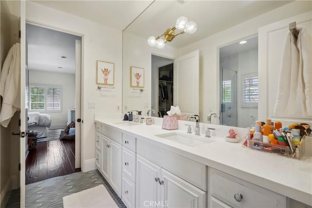 bathroom featuring connected bathroom, baseboards, a shower stall, and vanity