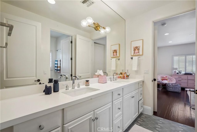 bathroom featuring a sink, wood finished floors, double vanity, and visible vents