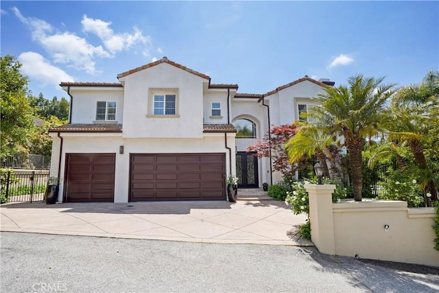 mediterranean / spanish-style house with fence, a garage, stucco siding, concrete driveway, and a tiled roof