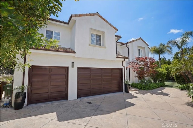 view of front of home with concrete driveway, an attached garage, a tile roof, and stucco siding