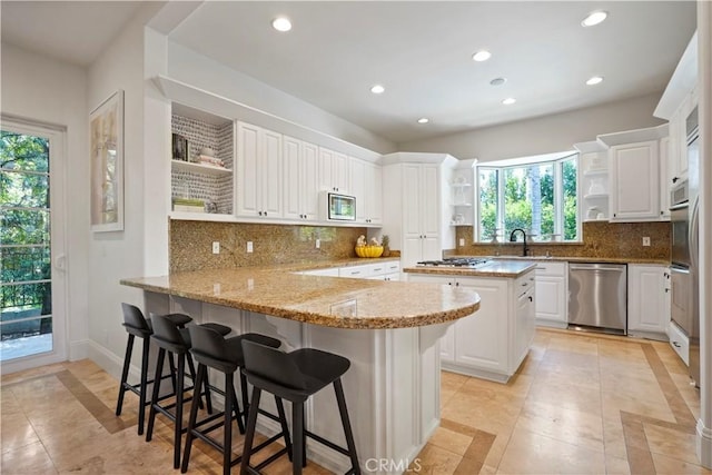 kitchen with decorative backsplash, open shelves, a peninsula, stainless steel appliances, and recessed lighting
