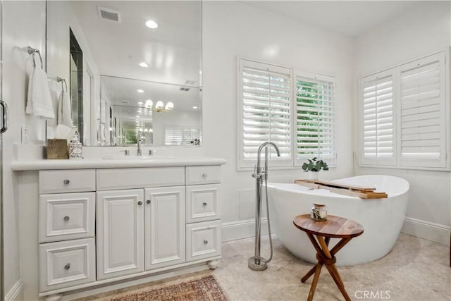 full bathroom featuring baseboards, visible vents, a freestanding tub, and vanity
