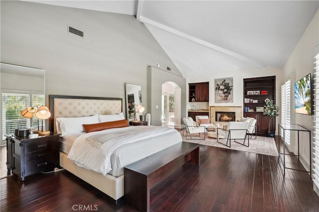 bedroom with wood-type flooring, arched walkways, high vaulted ceiling, and beamed ceiling