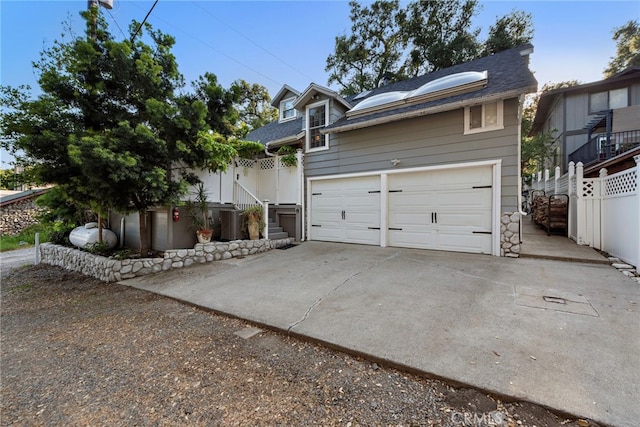 view of front of house featuring a shingled roof, central AC unit, driveway, and fence