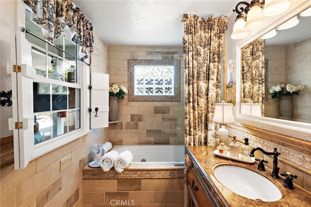 bathroom featuring vanity, a jetted tub, and tile walls