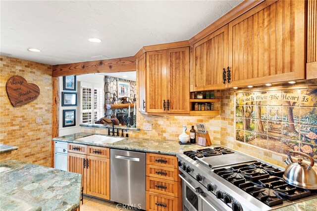 kitchen with decorative backsplash, stainless steel appliances, light stone counters, and a sink