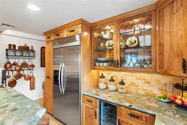 interior space featuring light stone countertops, beverage cooler, stainless steel built in fridge, brown cabinets, and tasteful backsplash