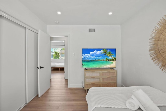 bedroom with baseboards, recessed lighting, wood finished floors, and visible vents