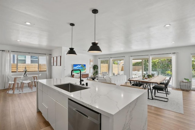 kitchen with a sink, a healthy amount of sunlight, stainless steel dishwasher, and open floor plan