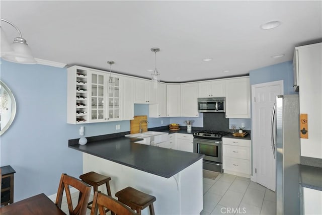 kitchen with a peninsula, dark countertops, and appliances with stainless steel finishes