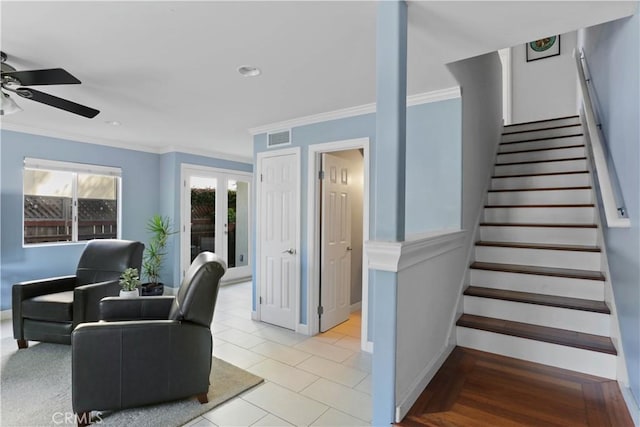 living area featuring ceiling fan, visible vents, stairway, baseboards, and ornamental molding