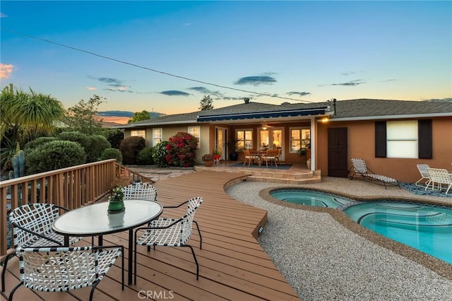 1215 Mira Monte Dr, Redlands, CA 92373 - back of property featuring an in-ground hot tub, outdoor dining space, a deck, and stucco siding