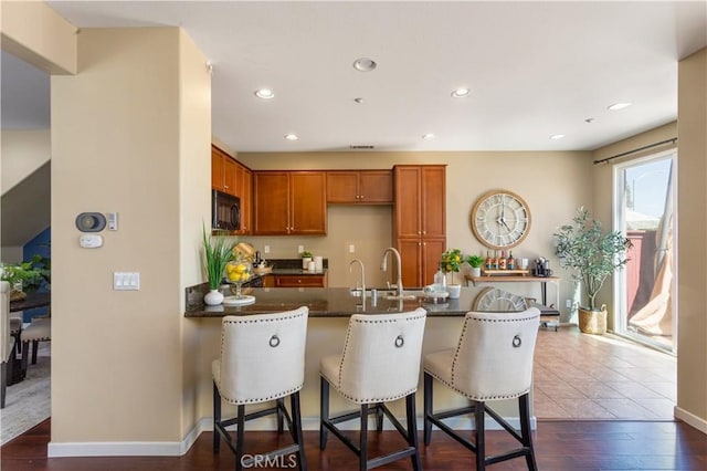 27441 Charleston Ct Unit 3, Murrieta, CA 92562 - kitchen featuring a kitchen bar, black microwave, dark countertops, brown cabinets, and a peninsula