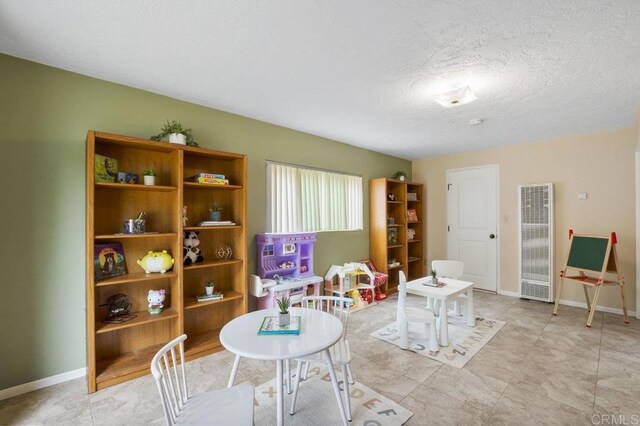 5566 Streamview Dr, San Diego, CA 92105 - playroom featuring baseboards, a textured ceiling, and a heating unit