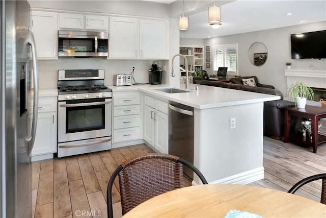 11818 Mount Harvard Ct, Rancho Cucamonga, CA 91737 - kitchen with appliances with stainless steel finishes, a sink, light wood-style floors, open floor plan, and a peninsula