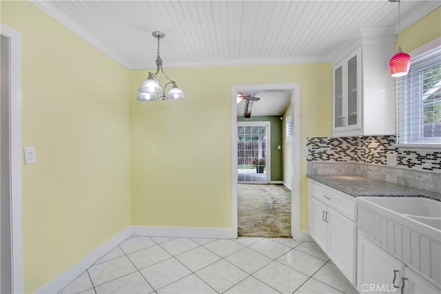 kitchen with white cabinetry, decorative light fixtures, light stone countertops, and glass insert cabinets