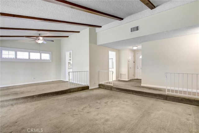 unfurnished living room with a textured ceiling, visible vents, beam ceiling, baseboards, and carpet
