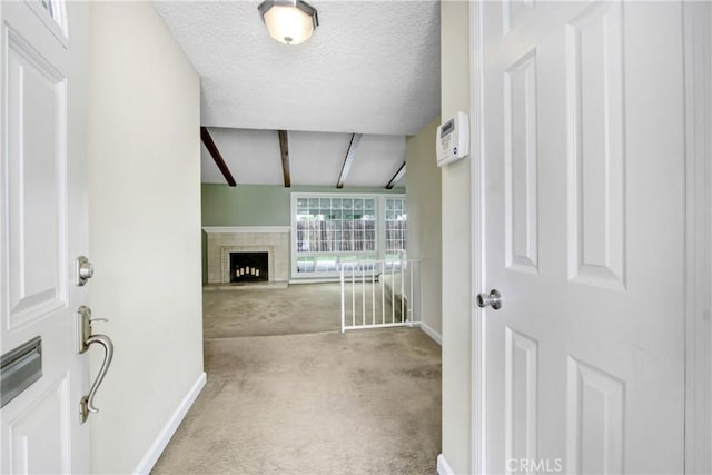 carpeted foyer featuring baseboards, vaulted ceiling with beams, a textured ceiling, and a fireplace