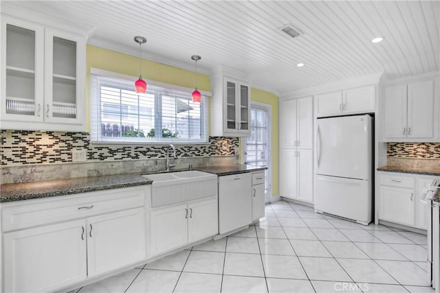 kitchen with plenty of natural light, backsplash, decorative light fixtures, white appliances, and white cabinetry