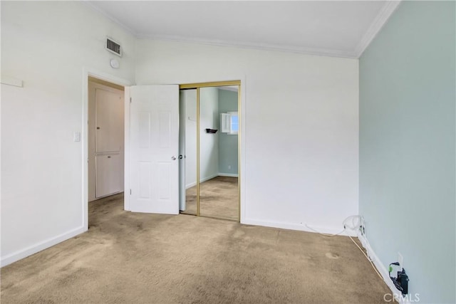unfurnished bedroom with carpet, baseboards, visible vents, ornamental molding, and a closet
