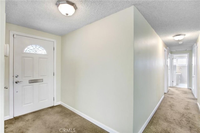carpeted entrance foyer featuring baseboards and a textured ceiling