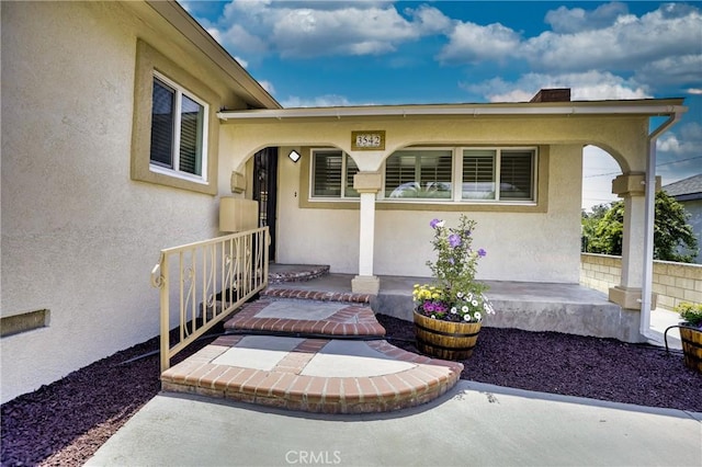 property entrance featuring covered porch and stucco siding