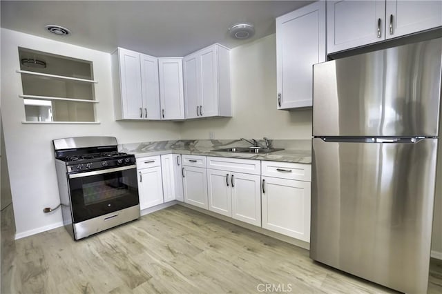 kitchen featuring a sink, appliances with stainless steel finishes, light wood finished floors, and white cabinetry