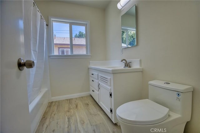 bathroom featuring vanity, wood finished floors, a healthy amount of sunlight, and toilet