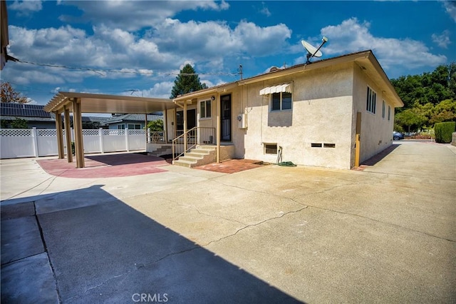 rear view of house with stucco siding and fence