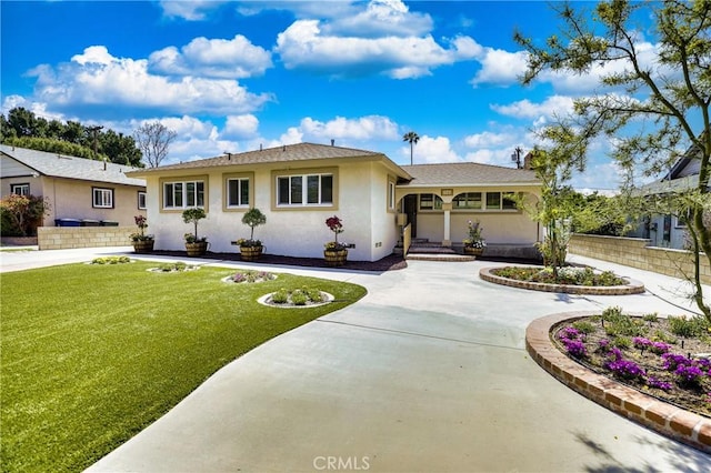 view of front facade with fence, curved driveway, a front lawn, and stucco siding