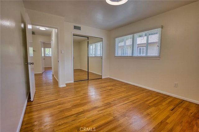 unfurnished bedroom featuring baseboards, visible vents, and light wood finished floors