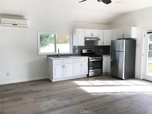 kitchen with backsplash, vaulted ceiling, a wall mounted air conditioner, a sink, and stainless steel appliances