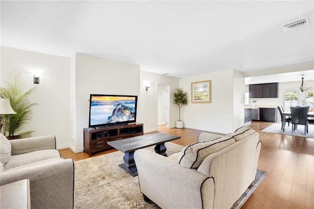 living room featuring visible vents, baseboards, and light wood-type flooring