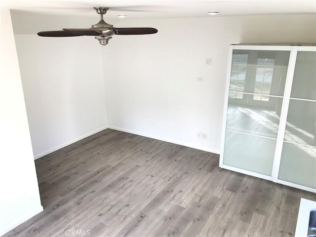 empty room featuring a ceiling fan, baseboards, and wood finished floors