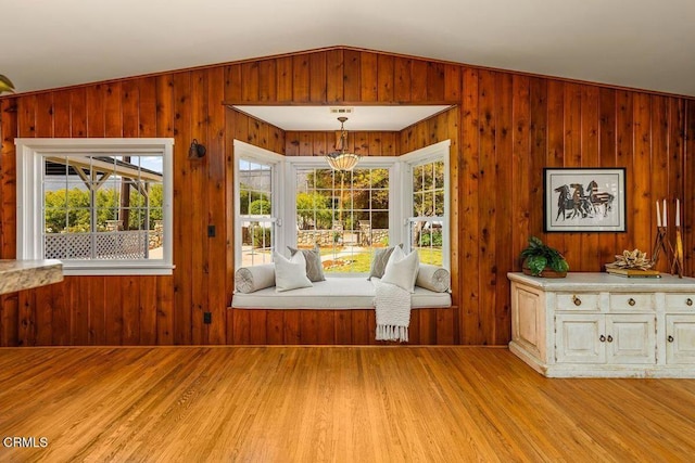 interior space with wood walls, plenty of natural light, light wood-style flooring, and lofted ceiling