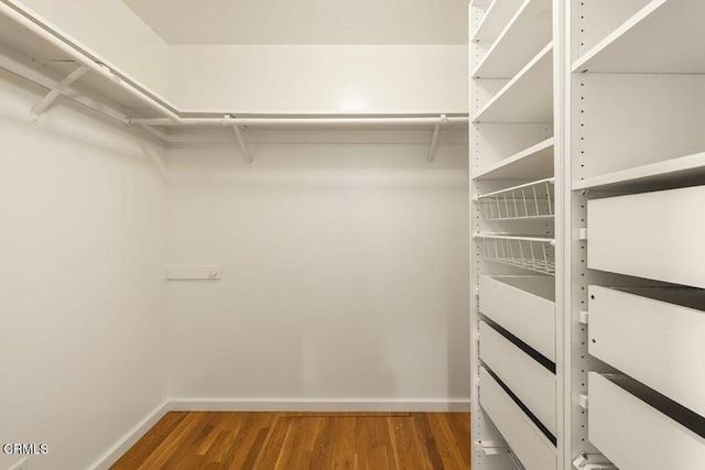 walk in closet with wood finished floors