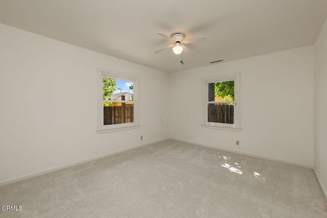 carpeted empty room featuring baseboards, a ceiling fan, and visible vents