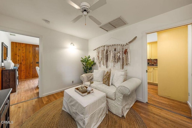 living area with visible vents, a ceiling fan, and light wood finished floors