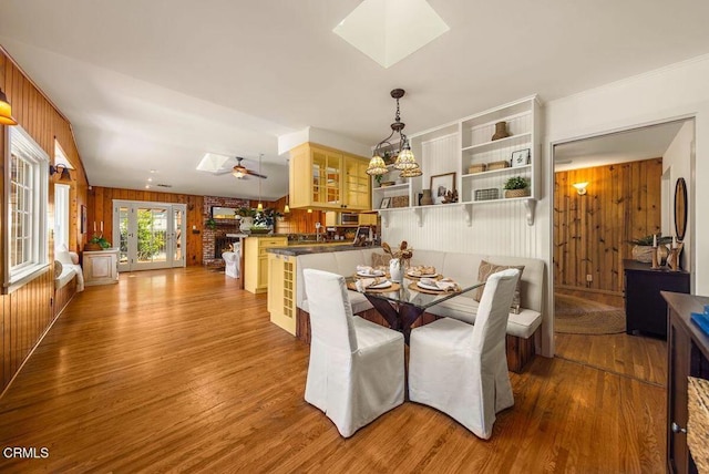 dining area featuring a skylight, wood walls, and wood finished floors